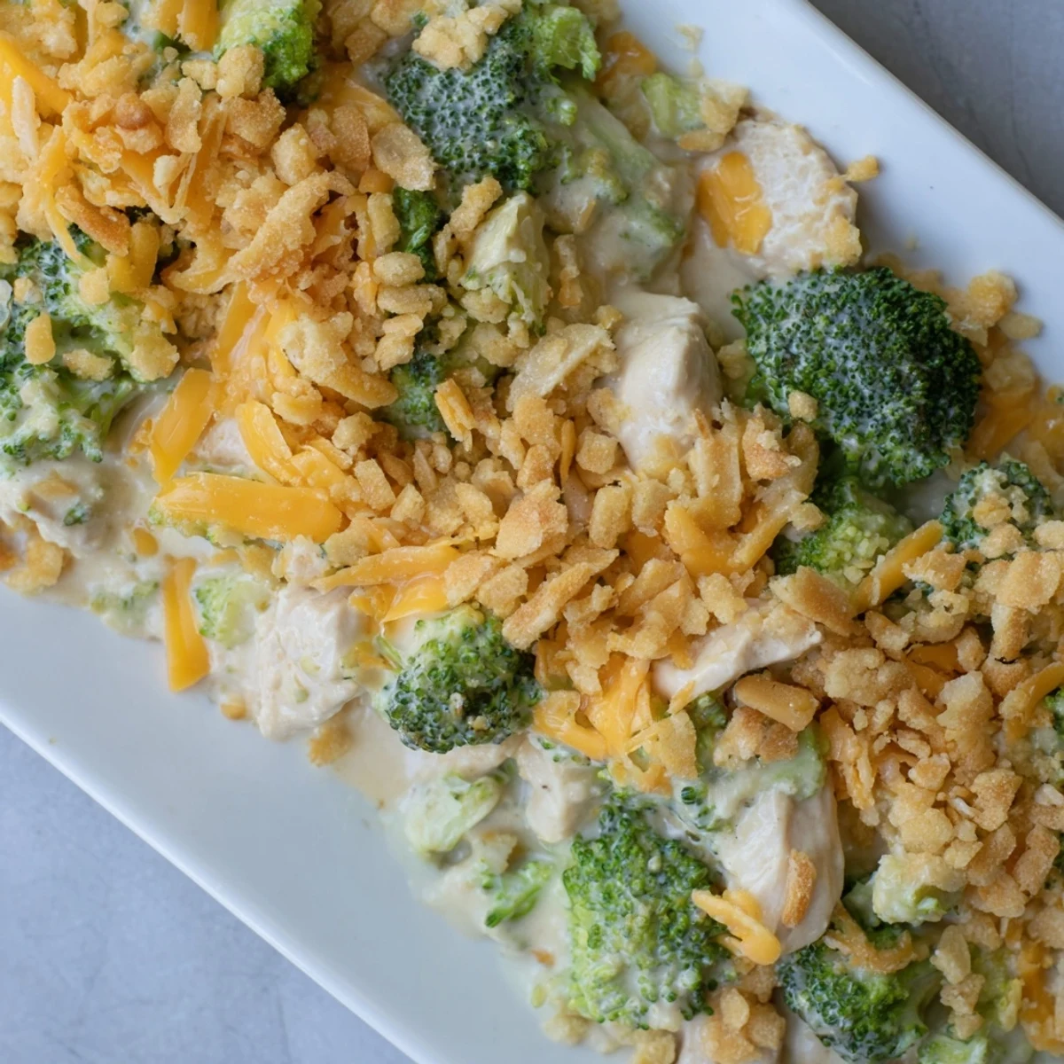 Steaming plate of Chicken & Broccoli Cheddar Bake with creamy sauce, chicken, and broccoli florets.