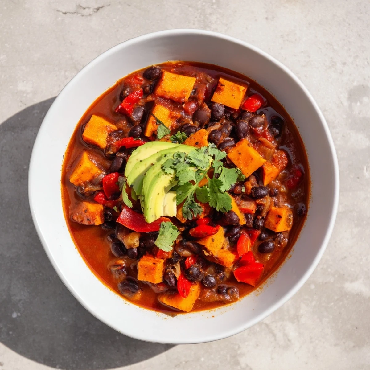 Steaming Sweet Potato & Black Bean Chili, rich with spices and topped with fresh cilantro, ready to eat.