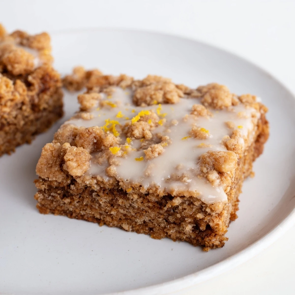 Enjoy a slice of homemade Lemon-Glazed Gingerbread Crumble Bars, perfect with a warm drink for the holidays.