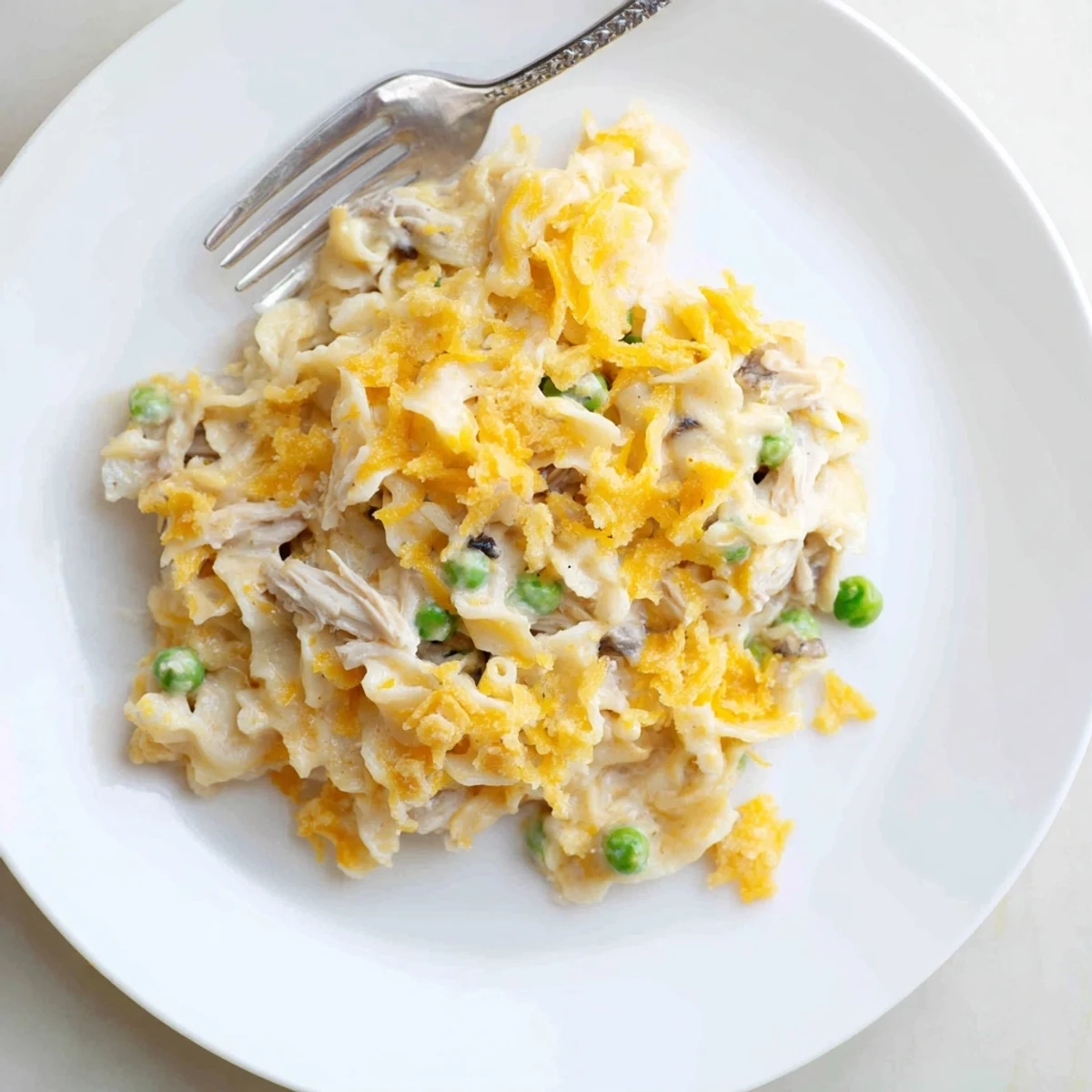 A close-up shot of a steaming, cheesy Creamy Tuna Noodle Casserole with fresh peas.