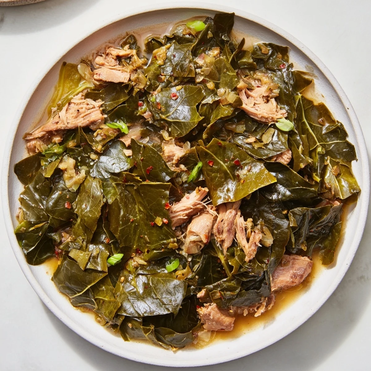 Savory Southern style collard greens simmering in a pot, served with the shredded smoked turkey.