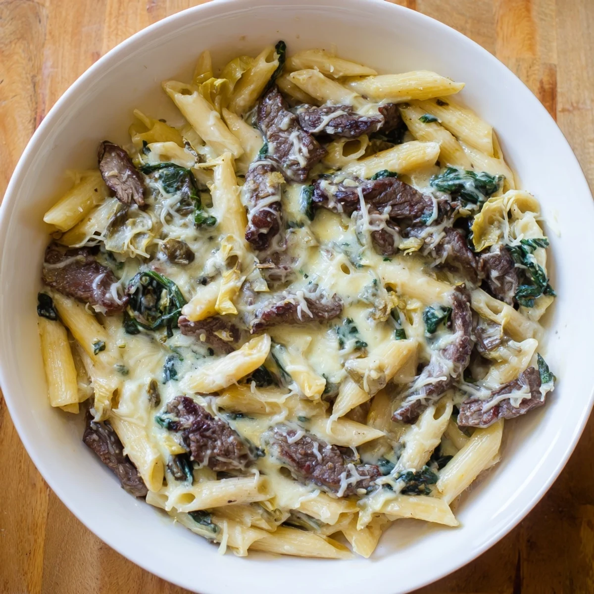 Imagine a close-up of the flavorful Steak & Spinach Artichoke Pasta, filled with creamy sauce, steak, and artichokes.