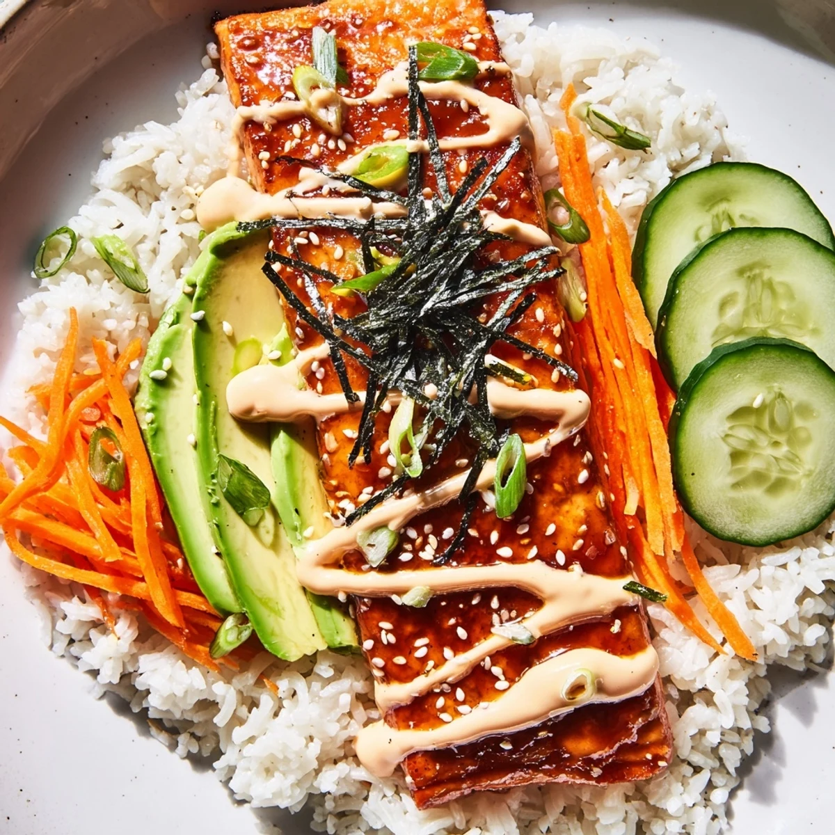 A beautifully presented teriyaki salmon rice bowl with glistening salmon pieces and fresh, colorful vegetables.