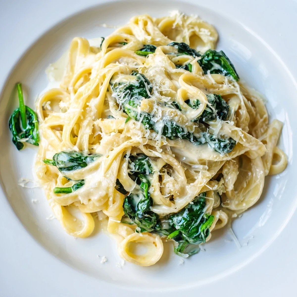 Steaming bowls of creamy garlic spinach pasta showcase wilted greens tossed in a luscious sauce.
