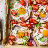 Sheet pan Tomato Feta Baked Eggs with glistening yolks, baked alongside juicy red tomatoes, ready to serve.