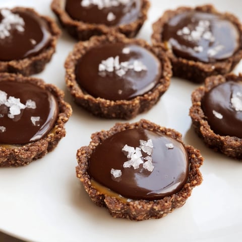 Decadent salted caramel chocolate tartlets topped with flaky sea salt and glossy ganache.