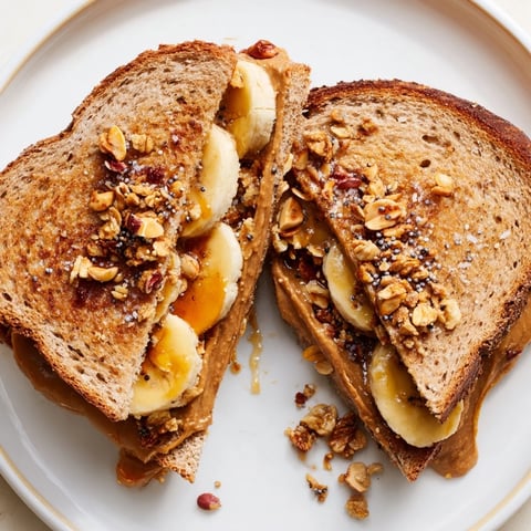 Gooey peanut butter and banana sandwich upgrade, toasted bread with crunchy toppings and sweet syrup.