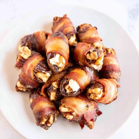 Crispy bacon wraps around sweet dates stuffed with cream cheese and walnuts, a delicious appetizer.