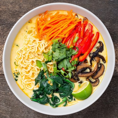 A steaming bowl of Curry Coconut Ramen with colorful veggies and fresh cilantro garnish.
