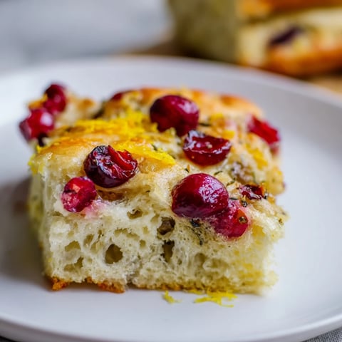 Golden brown Cranberry Orange No-Knead Focaccia topped with bright red cranberries and a hint of orange.