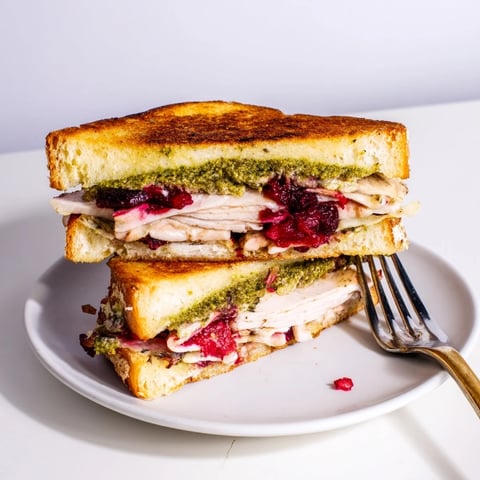 Golden, gooey Pesto Cranberry Turkey Grilled Cheese Melt, piled with turkey and cheese, ready to eat.
