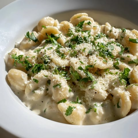 Creamy ditalini pasta glistening, bathed in a rich garlic sauce with fresh parsley garnish.