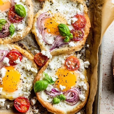 Golden Tomato Feta Baked Eggs, served hot from the sheet pan with creamy feta and fresh basil.