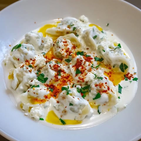 Steaming hot Turkish cheesy manti dumplings, coated with a creamy yogurt sauce and spiced butter.