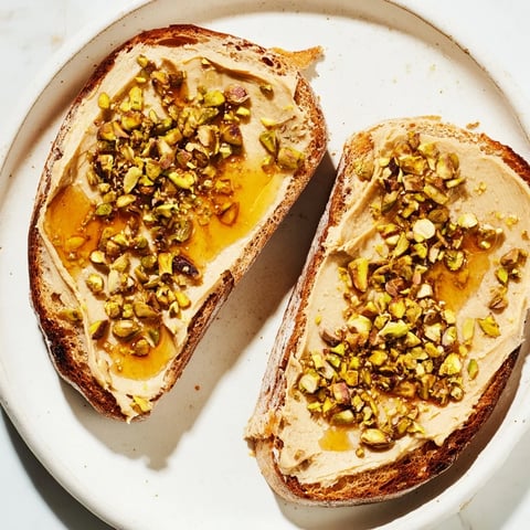 Warm, golden-brown Pistachio Butter Toast topped with glistening honey and crunchy pistachios.