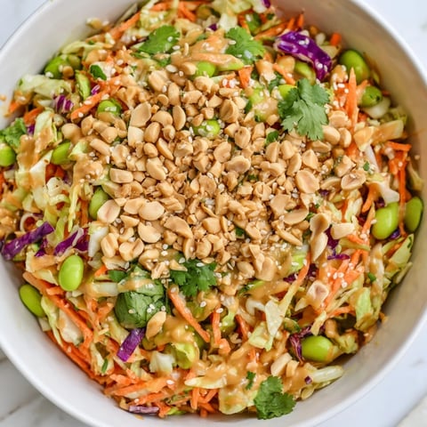 Bright green cabbage, shredded carrots, and red bell peppers are tossed in creamy peanut dressing for this Crunchy Thai Peanut Salad.