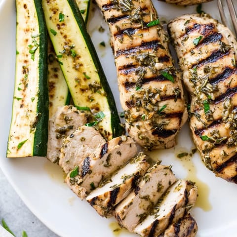 Flavorful grilled chicken breasts paired with vibrant zucchini, garnished with fresh herbs.  