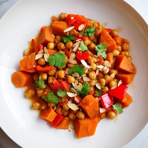 Hearty Moroccan chickpea & sweet potato tagine, showcasing vibrant vegetables and a rich, flavorful broth.