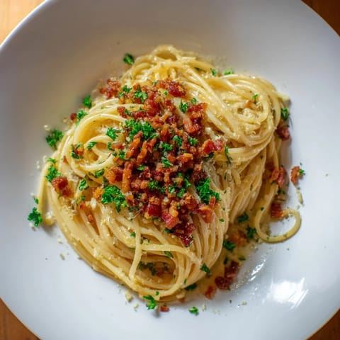 Steaming bowl of Garlic Butter Pasta highlighted with crispy bacon and fresh parsley for a flavorful meal.