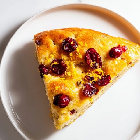 A close-up of fluffy Cranberry Orange No-Knead Focaccia with glistening olive oil and sugared cranberries.