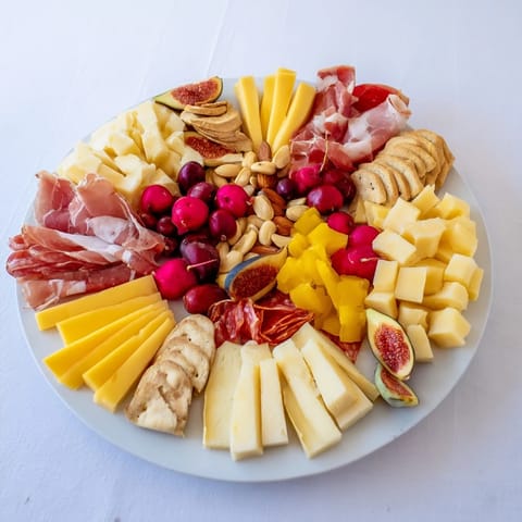 Cheval Heureux Snack Board overflowing with colorful cheeses, meats, fresh fruit and crisp crackers.