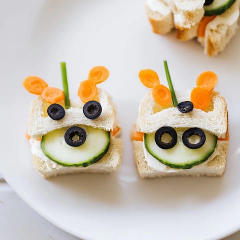 Cute bee sandwich cutouts feature black olive stripes and chive antennae ready to eat.