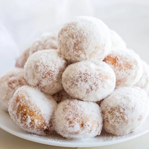 A close-up of a delightful powdered donut holes mountain, with sweet, sugary spheres perfect for sharing.