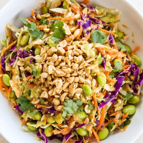 A vibrant, crunchy salad featuring shredded carrots, cabbage, and edamame, tossed in a creamy, tangy peanut dressing. Perfect as a refreshing side or light meal.