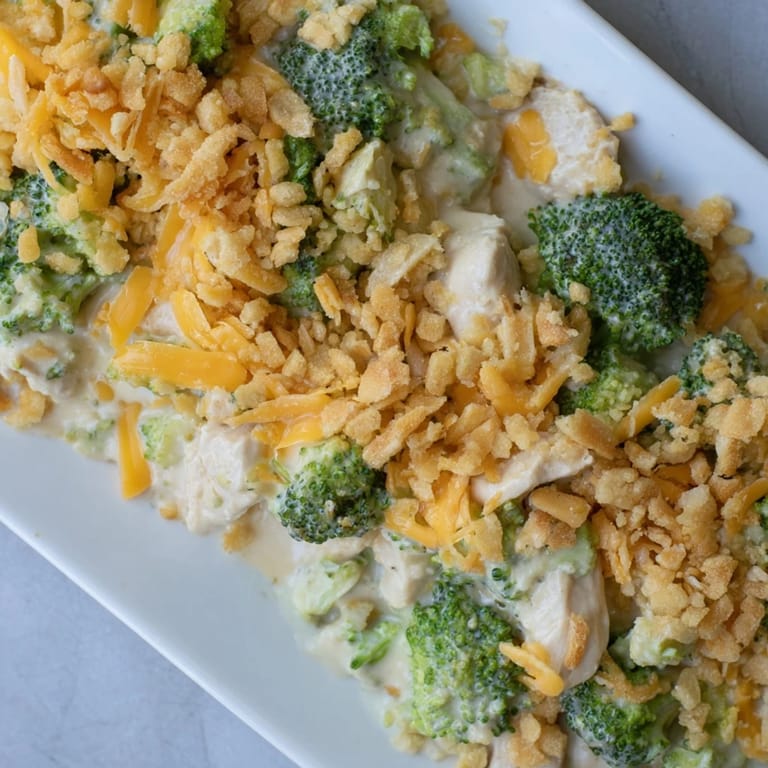 Steaming plate of Chicken & Broccoli Cheddar Bake with creamy sauce, chicken, and broccoli florets.