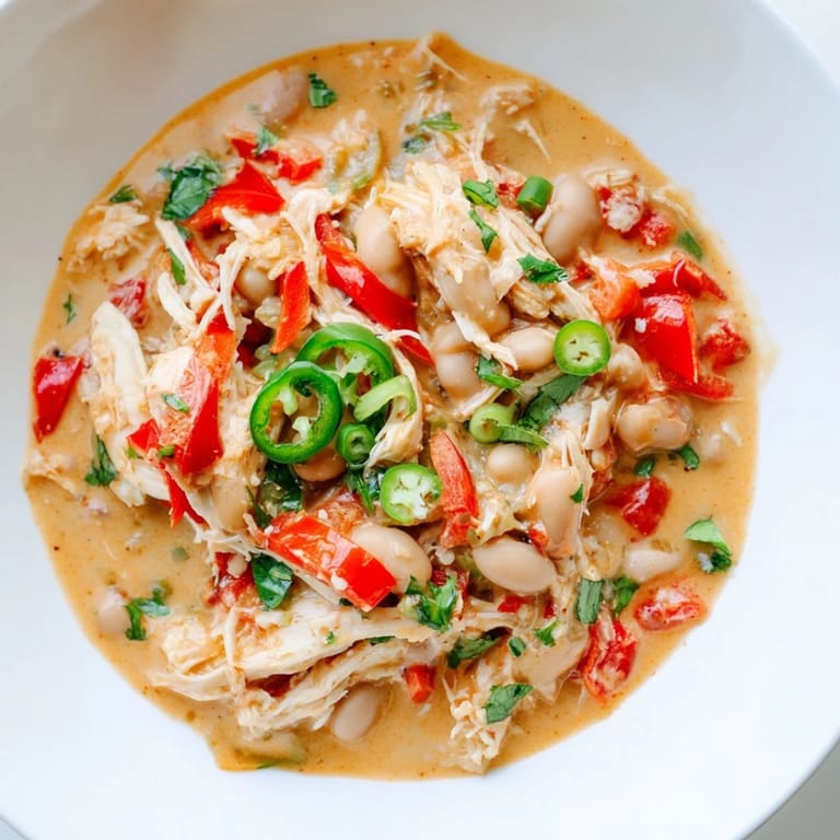 Tender chicken and creamy beans simmer in a pot of spice, preparing a Creamy White Chicken Chili.