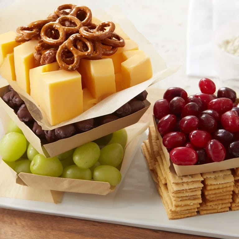 Colorful Stacked Christmas Gift Snack Tower featuring cheese cubes, pretzels, and wrapped boxes filled.