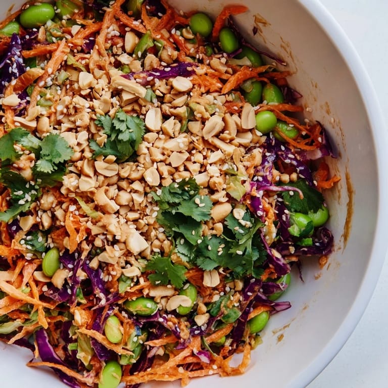 Fresh lime wedges and chopped roasted peanuts garnish a colorful bowl of Crunchy Thai Peanut Salad, perfect for a light vegetarian meal.