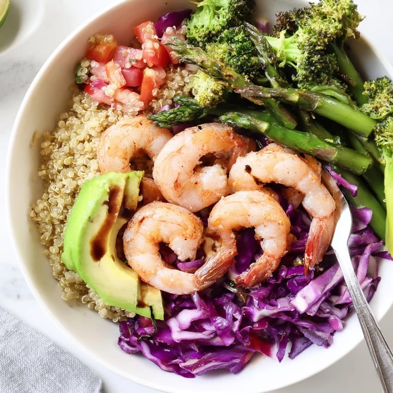Fluffy quinoa and pink shrimp fill a detox Buddha bowl, garnished with fresh tomatoes, crunchy cabbage, and a balsamic drizzle.  