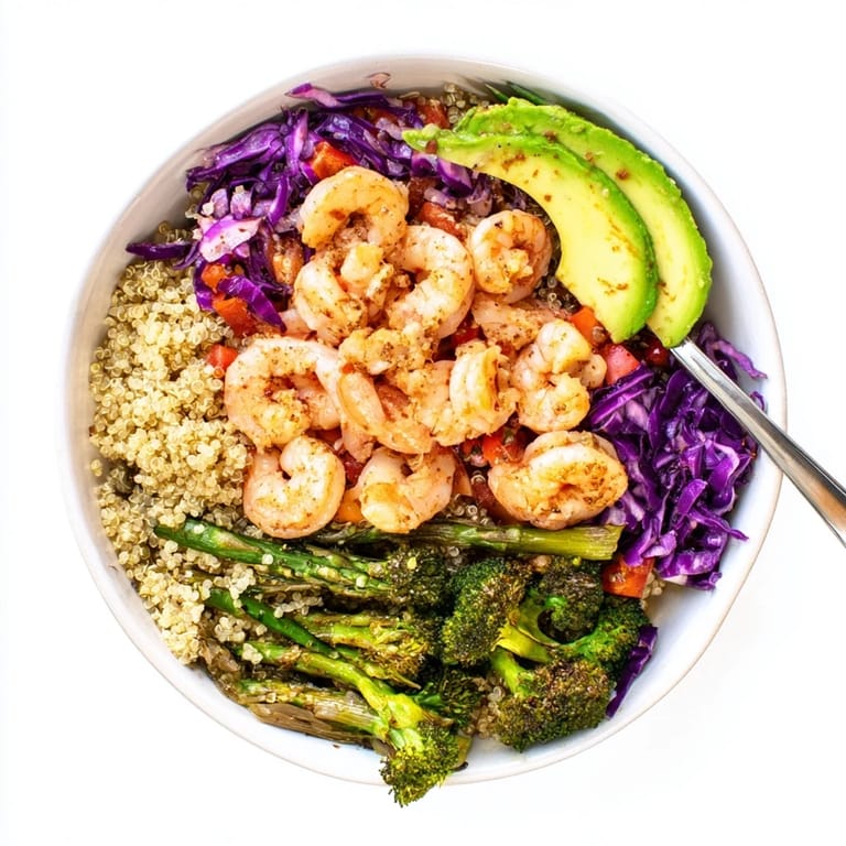 Colorful detox Buddha bowl with sautéed shrimp, quinoa, roasted veggies, and creamy avocado, ready for a healthy lunch.