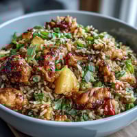Sweet chili chicken pineapple fried rice with tender chicken, juicy pineapple, and vibrant vegetables in a zesty sauce, served hot in a wok.