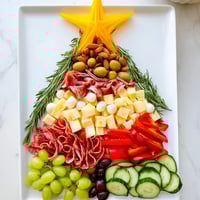Christmas Tree Snack Board laden with cheeses, meats, and vibrant fruits, perfect for holiday parties.